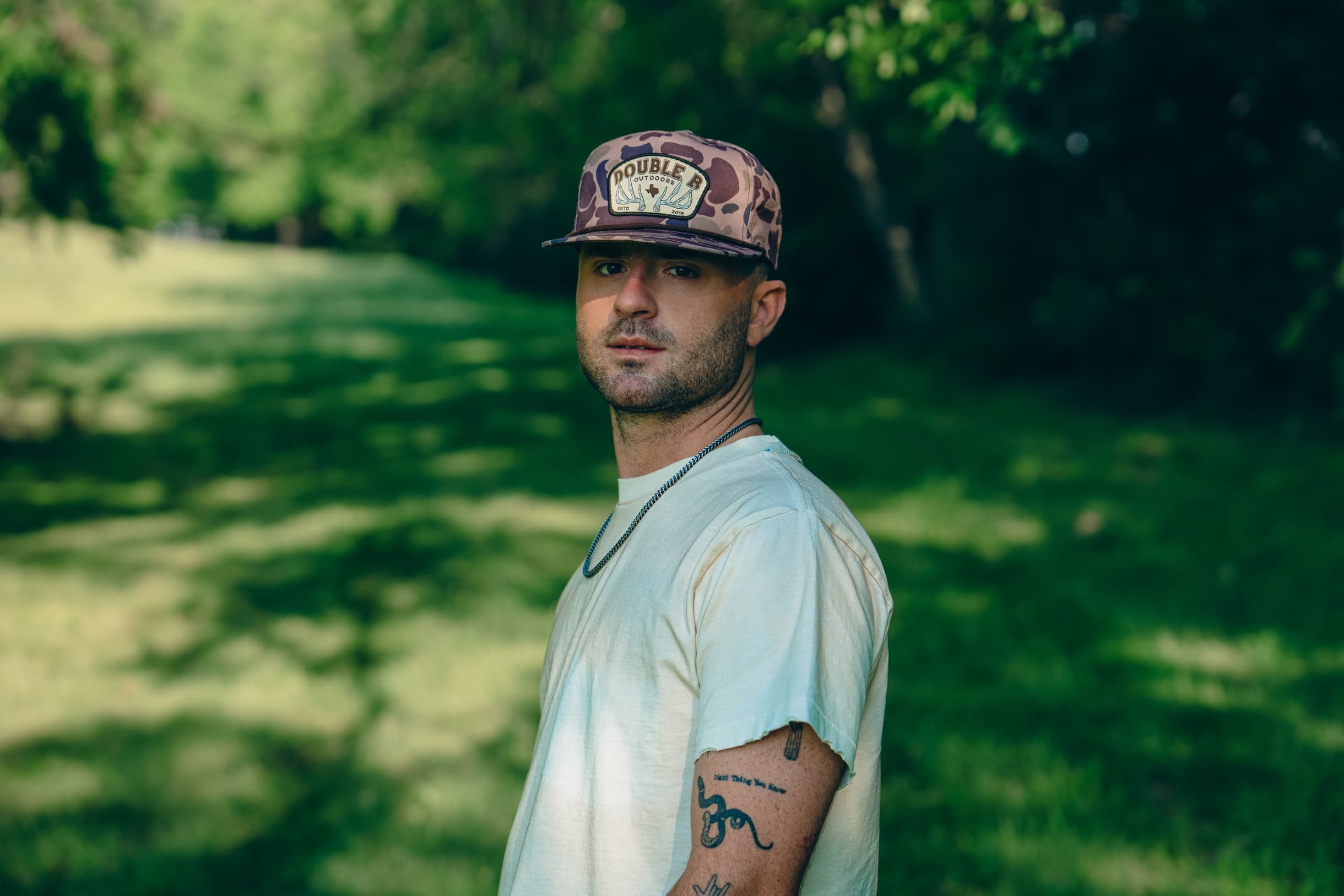Greylan James outdoors in a camo ball cap